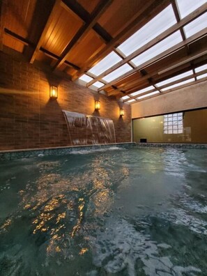 Une piscine intérieure avec un plafond en bois et des murs en briques.