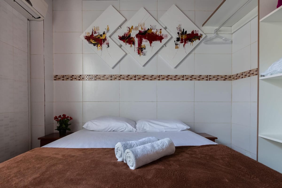 Une chambre d’hôtel avec un lit, une serviette marron et trois tableaux abstraits accrochés au mur.