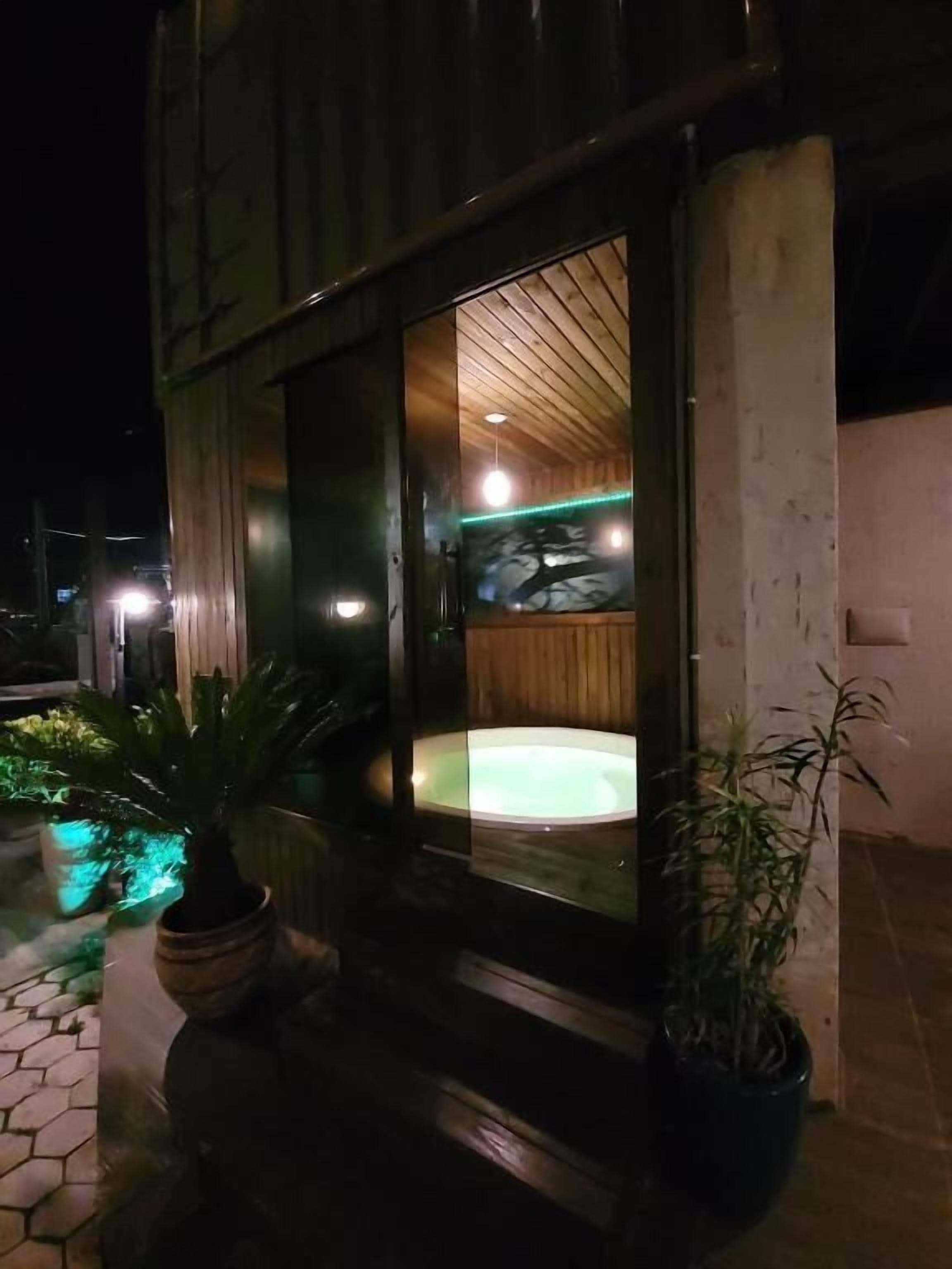A modern building with a glass entrance, a wooden interior, and a hot tub outside.