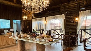 A rustic dining area with a large wooden table, chairs, and a chandelier. - Pousada Recanto do Aconchego (Florianópolis)