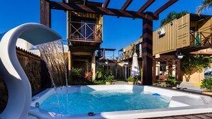 A hot tub with a waterfall feature, surrounded by wooden structures and plants. - Pousada Recanto do Aconchego (Florianópolis)