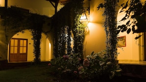 A covered outdoor area with a wooden door, a hanging light fixture, and lush greenery. - Bremen Hotel & Spa (Villa General Belgrano)