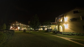 A well-lit hotel with multiple buildings, a paved pathway, and a well-maintained lawn. - Bremen Hotel & Spa (Villa General Belgrano)