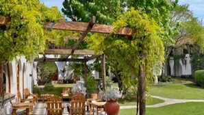 A covered outdoor seating area with wooden furniture and a pergola. - Bremen Hotel & Spa (Villa General Belgrano)