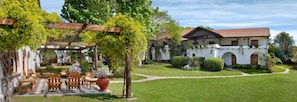 A courtyard with outdoor seating, a white building with arches, and a red-tiled roof. - Bremen Hotel & Spa (Villa General Belgrano)
