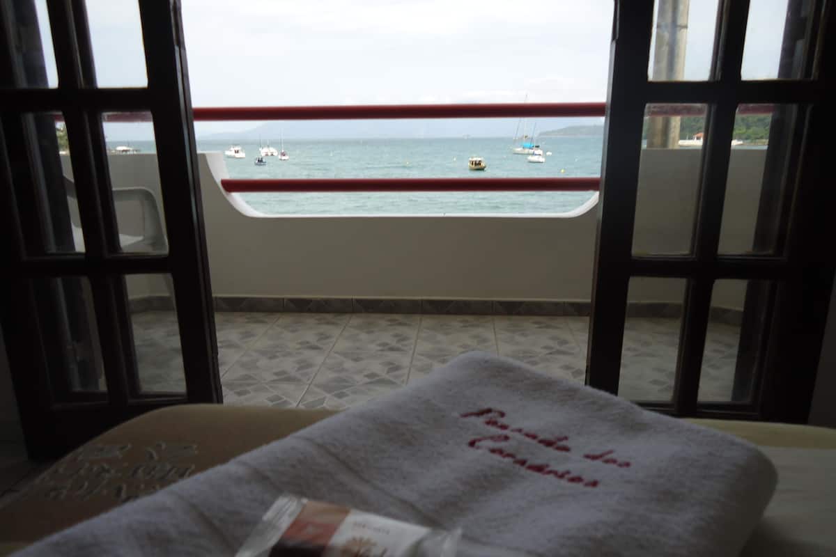 A room with a view of the sea through a window with metal bars.