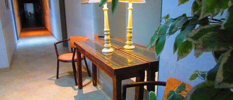 A dining area with a wooden table and chairs, a lamp, and a plant.