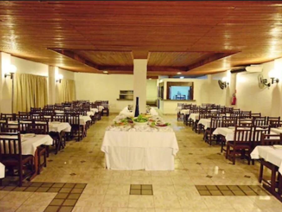A banquet hall with rows of tables and chairs, a central buffet table, and a wooden ceiling.