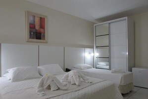 Habitación de hotel con dos camas, un espejo grande y un armario.