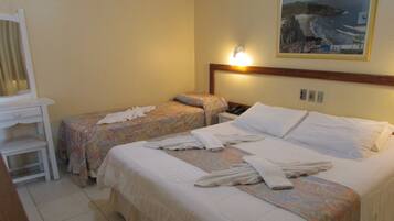 Habitación de hotel con dos camas, una silla y una lámpara fijada a la pared.