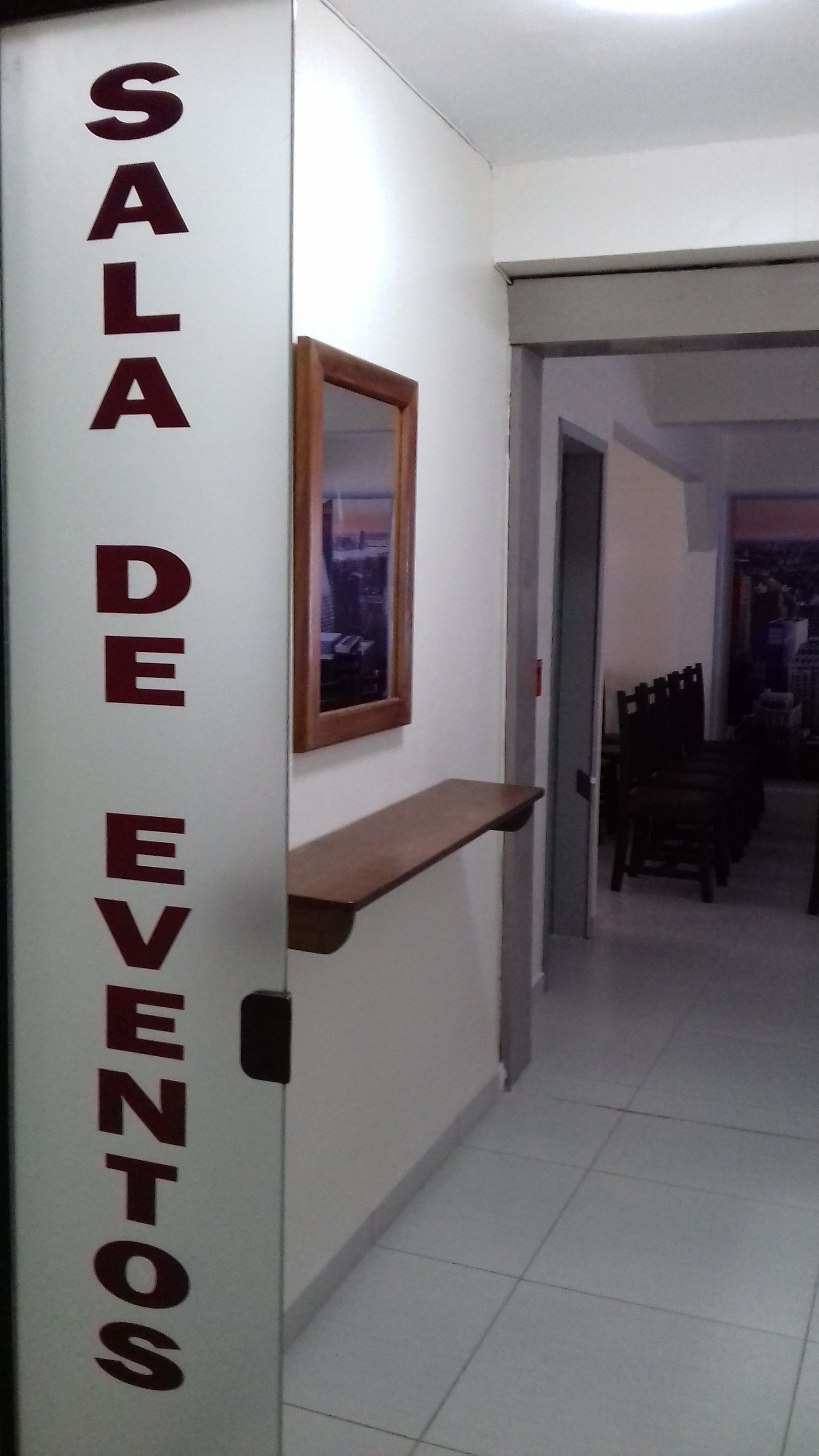 A hallway with a sign reading "SALA DE EVENTOS" and a wooden shelf.