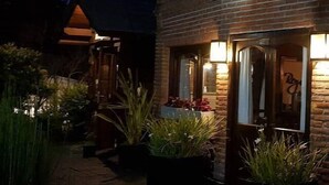 A brick building with a door and windows, surrounded by potted plants. - Rey del Bosque (Valeria del Mar)