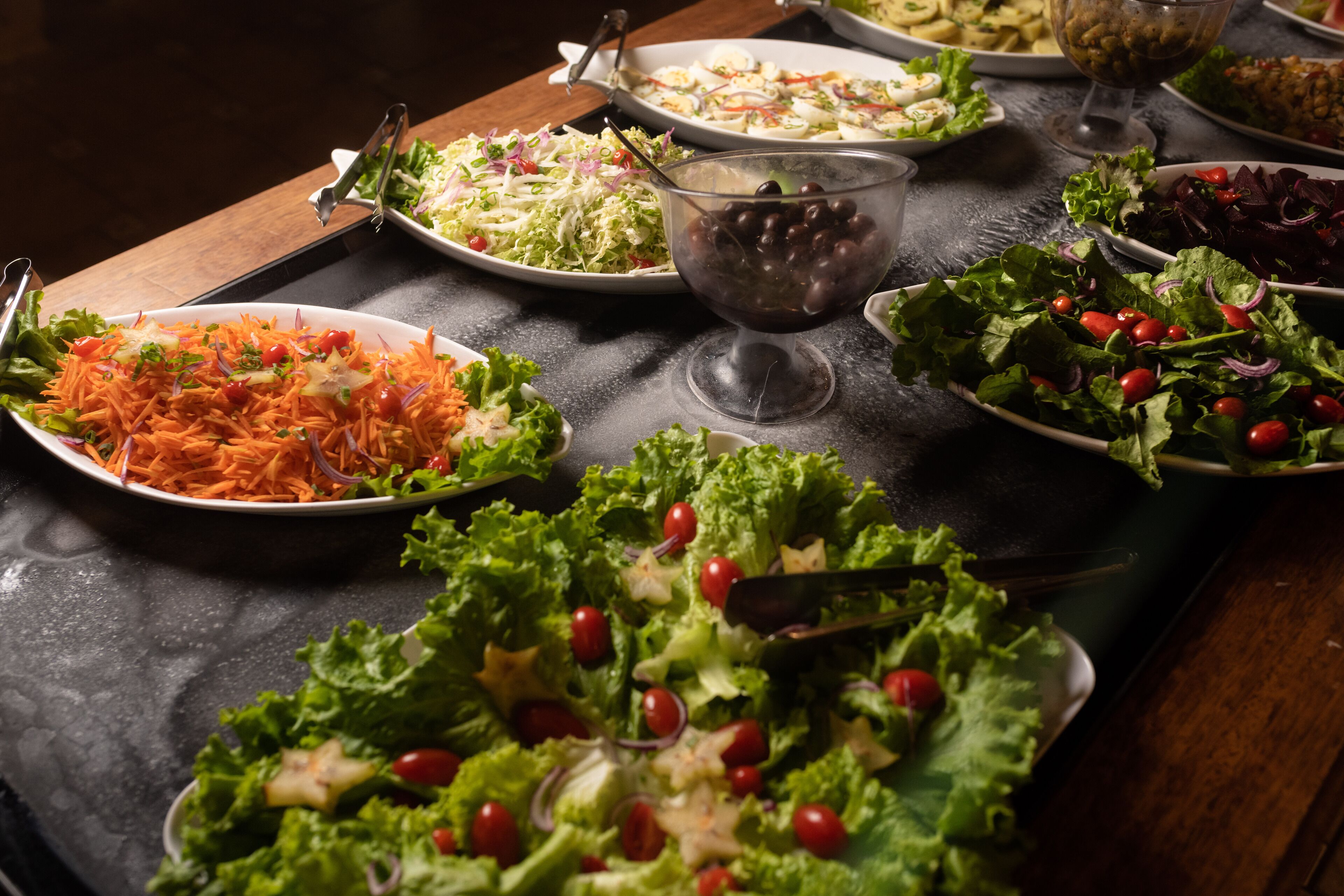 A table with various salads and a bowl of olives.