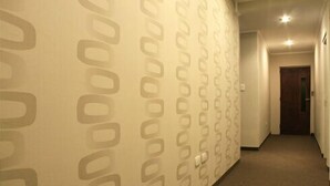 A hallway with patterned wallpaper and a carpeted floor. - Hotel Marconi (Resistencia)