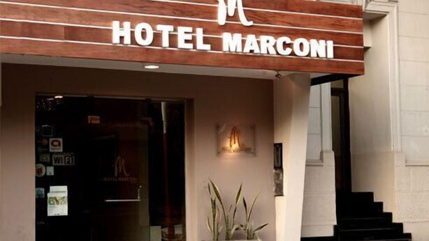 The exterior of Hotel Marconi with a wooden facade, a glass entrance, and a staircase leading to the entrance. - Hotel Marconi (Resistencia)