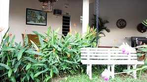 A white bench in a garden area with tropical plants and a hanging lantern. - Hotel Flamboyant (Olímpia)