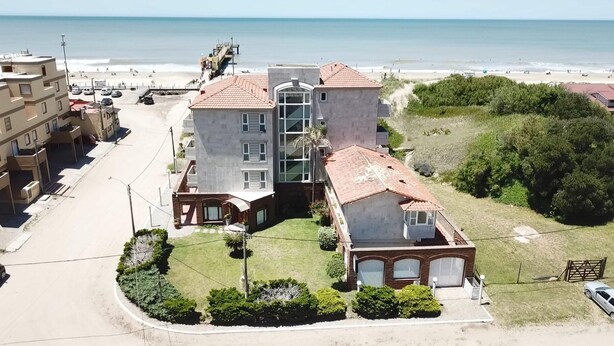 Un edificio de varios pisos con un patio central, junto a la playa.