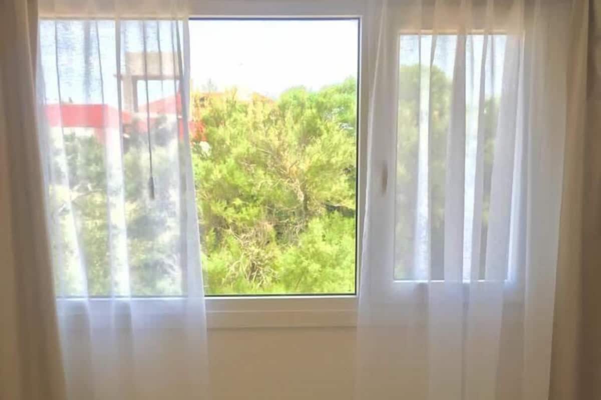 Habitación de hotel con cama, ventana con cortinas y vistas al exterior.