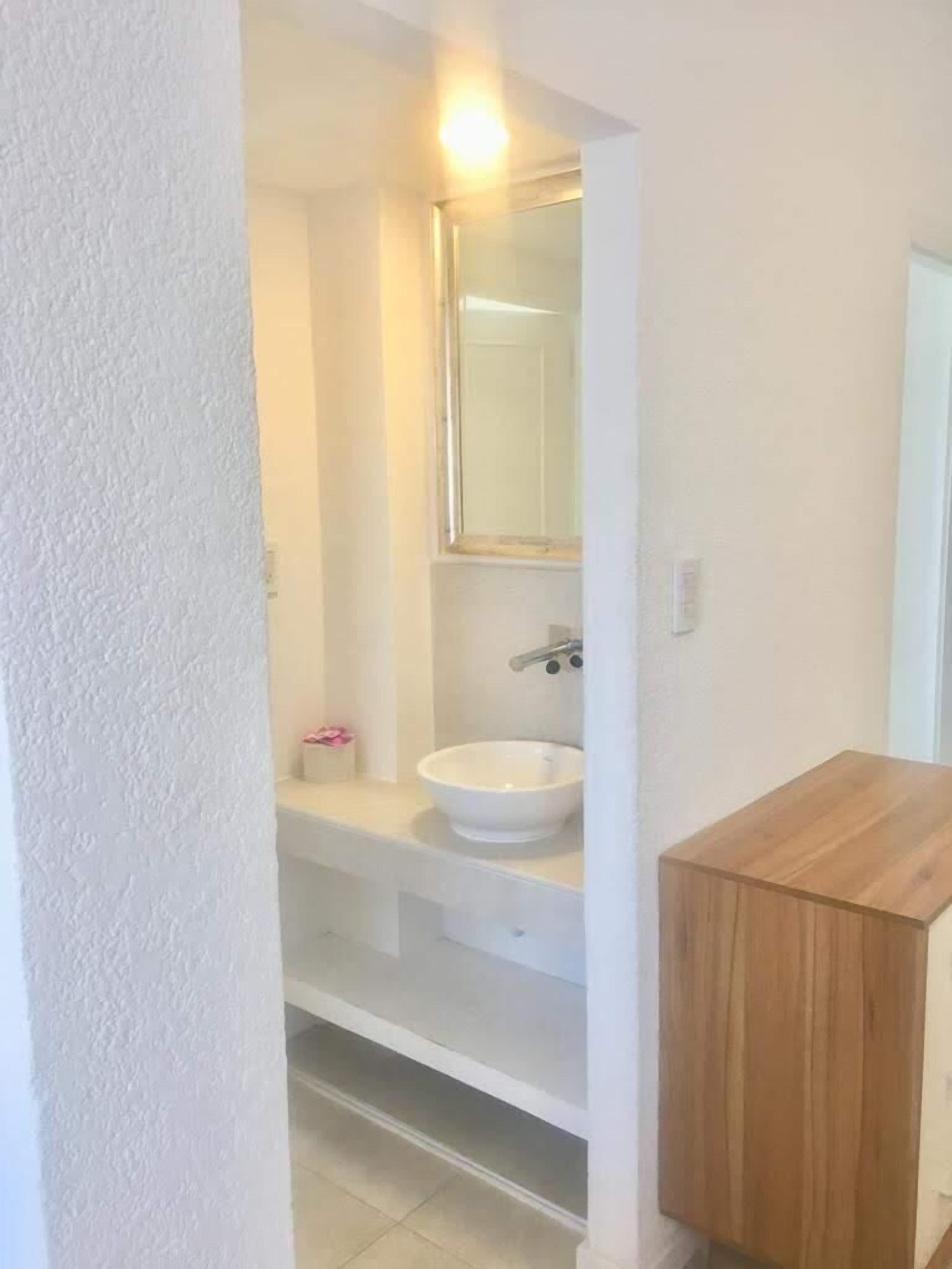 A bathroom with a white sink, a mirror, and a wooden cabinet.