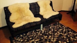 Un divano con coperta a quadri e un tappeto intrecciato su un pavimento di legno.