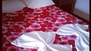 Un letto con una coperta a fiori, due asciugamani bianchi e una testiera in legno.