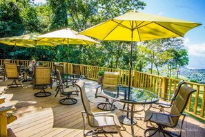 Une terrasse extérieure avec des parasols jaunes, des chaises en osier et une table à plateau en verre.