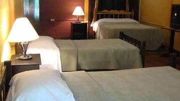 Una habitación de hotel con dos camas individuales, una mesita de noche con lámpara, un cabecero de madera y un televisor.