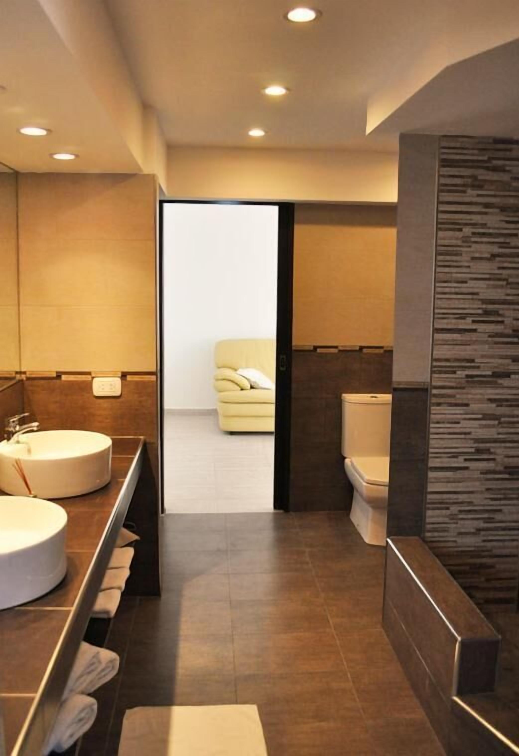 A modern bathroom with a large mirror, a round sink, and a toilet.