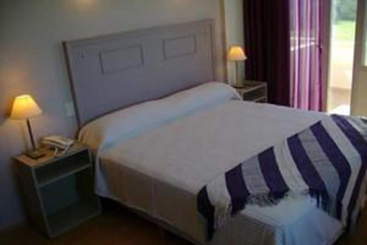 A neatly made bed with a striped blanket, a bedside lamp, and a nightstand with a phone.