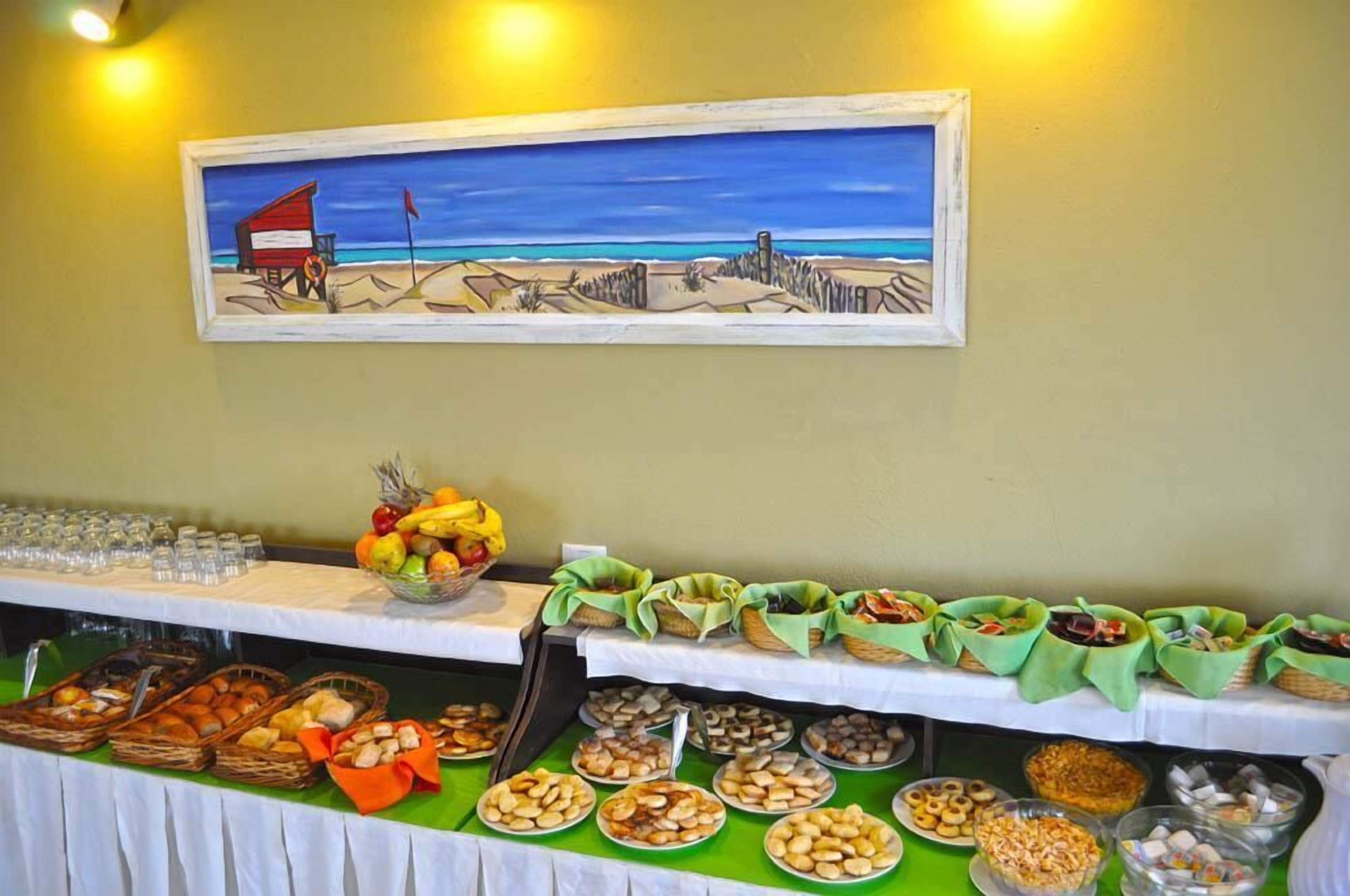 A buffet table with various food items and a painting of a beach scene above it.
