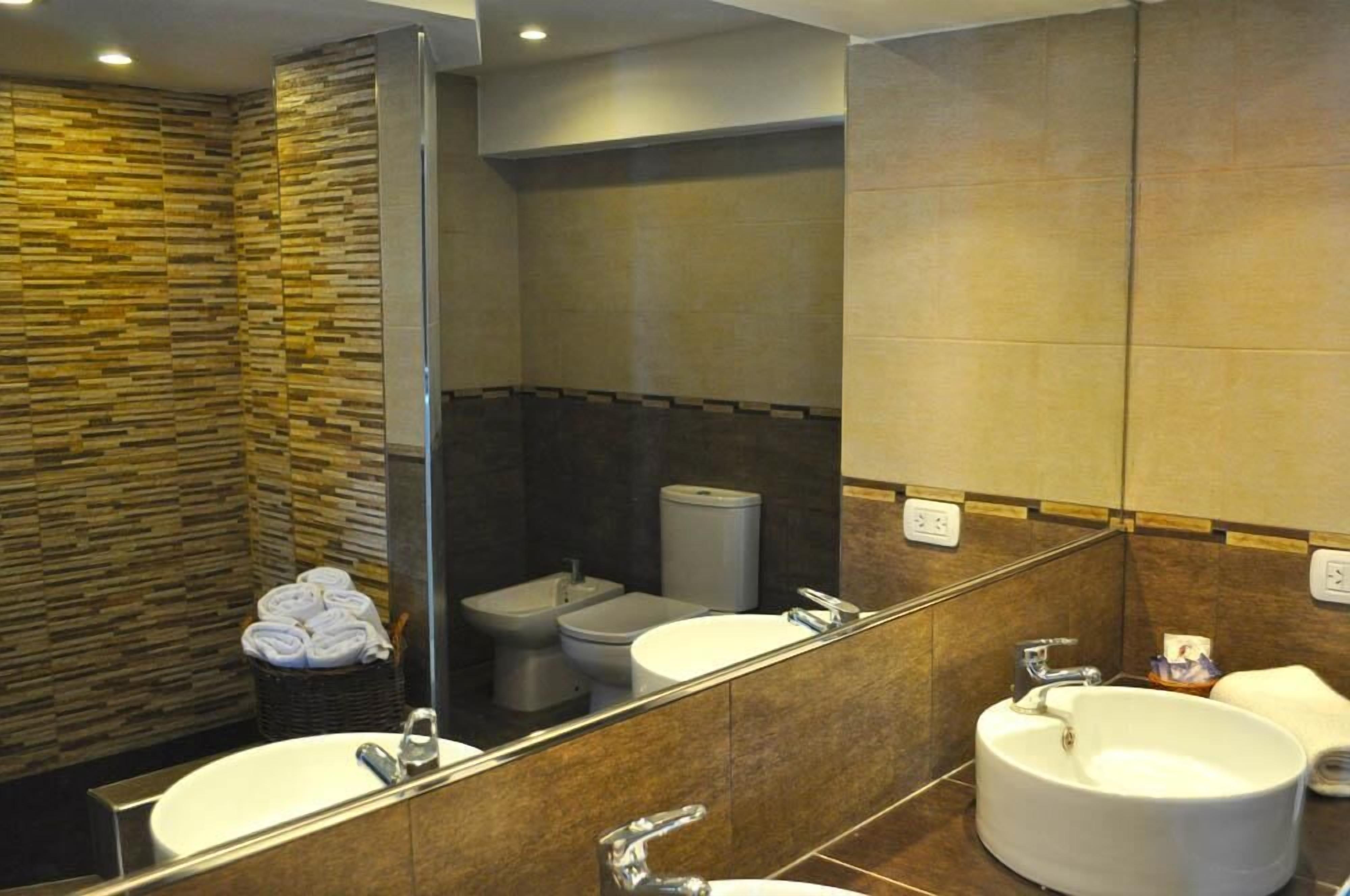 Un baño moderno con un espejo grande, dos lavamanos, un inodoro y un bidé.