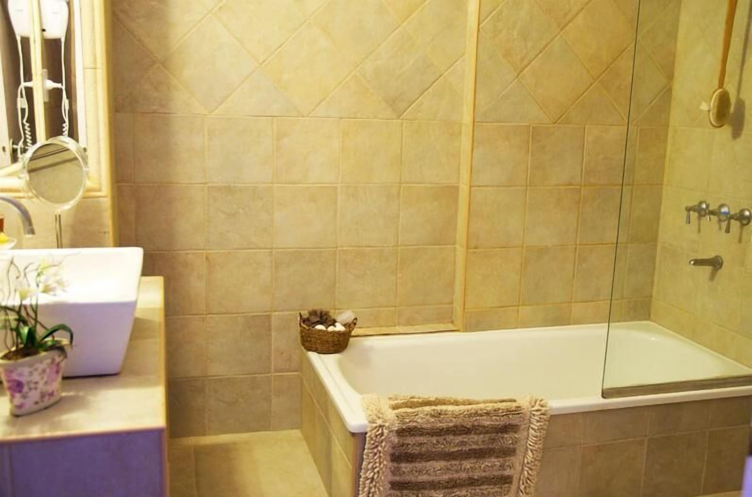 Un baño con una bañera, un lavabo con espejo y una planta en maceta.