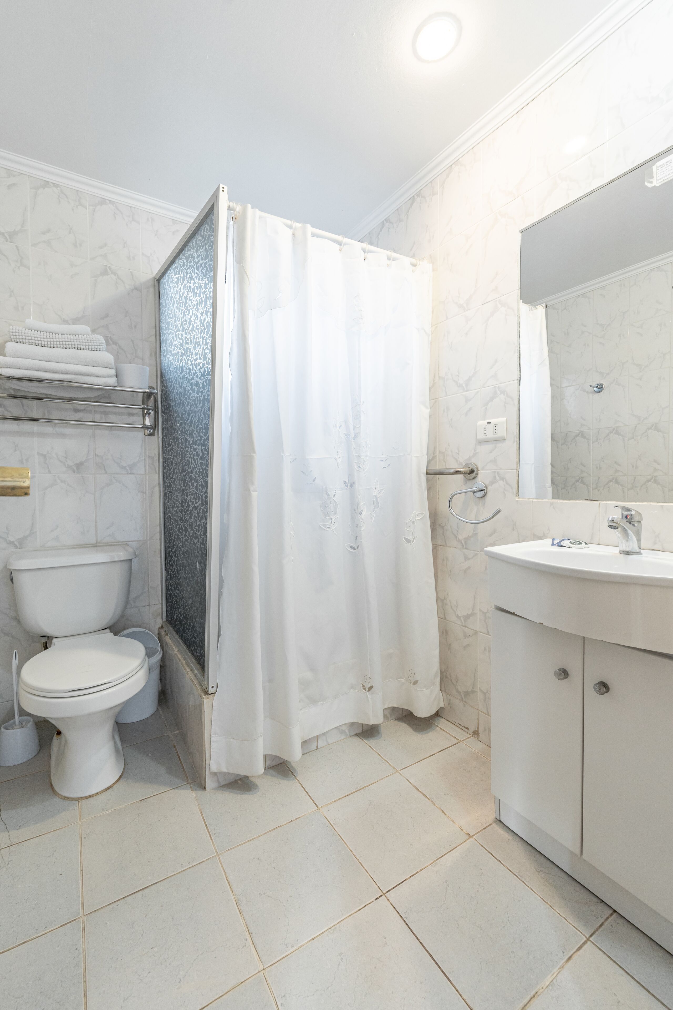 A bathroom with a toilet, shower, and sink.