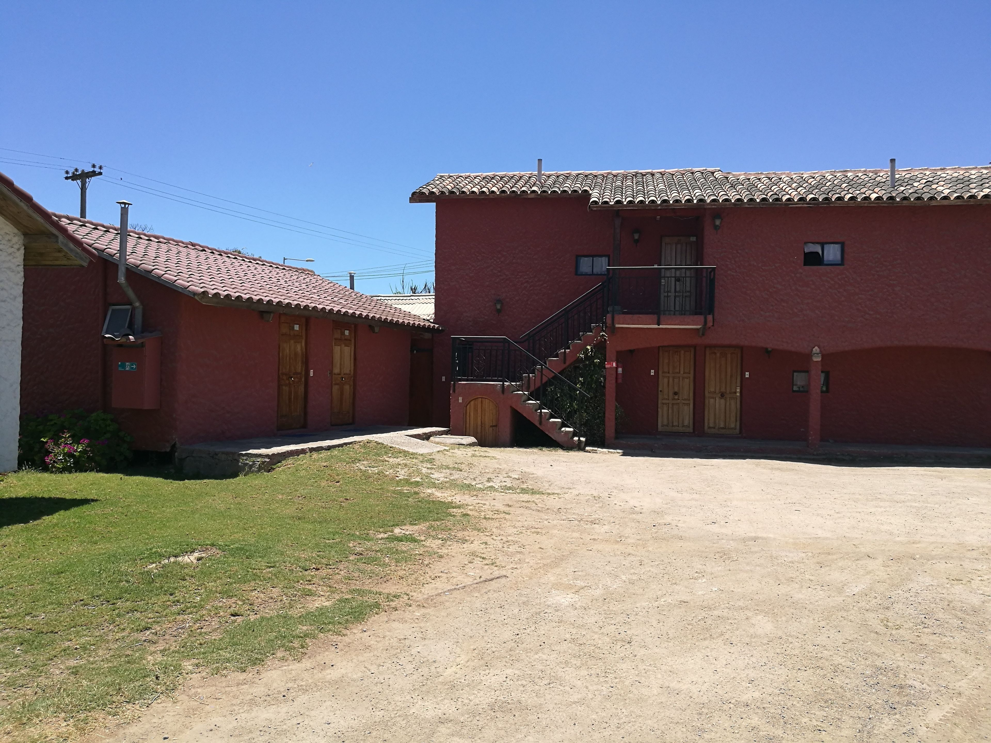 A red building with a tiled roof, a staircase, and a small garden area.