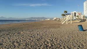 Ein Strand mit einem Rettungsturm, Palmen und Gebäuden im Hintergrund.