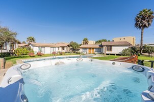 Un jacuzzi rodeado por una piscina, con un cielo azul despejado.