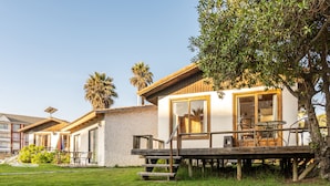 Ein modernes Haus mit einer Terrasse, Sitzgelegenheiten im Freien und einem gepflegten Rasen.