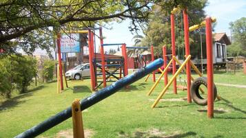 Un parque infantil con un columpio de neumático y un tobogán.