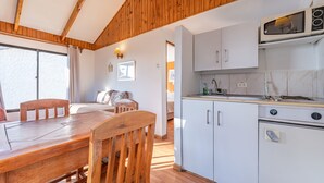 Eine Küche mit Holzbalkendecke, weißen Schränken und einer Mikrowelle.