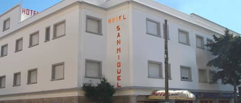 A multi-story hotel with a prominent vertical sign reading "HOTEL SAN MIGUEL."