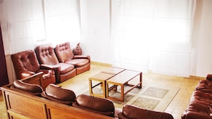 Ein Wohnzimmer mit einem braunen Ledersofa, einem Holztisch und einem gemusterten Teppich.