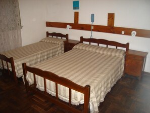 Two single beds with wooden frames and headboards, a small bedside table, and a wall-mounted telephone. - Hotel San Miguel (San Bernardo del Tuyú)