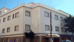 Ein mehrgeschossiges Hotel mit schlichter Fassade, zahlreichen Fenstern und einem gut sichtbaren Hinweisschild, das es als Hotel kennzeichnet.