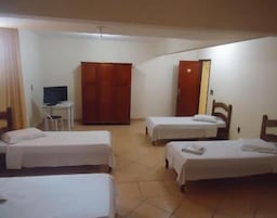 Una habitación de hotel con dos camas individuales, televisión, armario y escritorio.