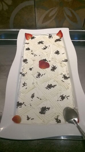 A rectangular white plate with a white dessert, strawberries, and chocolate shavings. - Hotel Trilhos de Minas (São João del Rei)