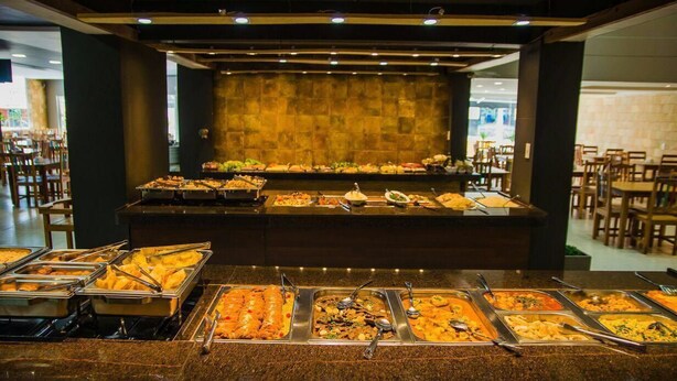 Ein reichhaltiges Buffet mit verschiedenen Speisen in einem hell erleuchteten Essbereich mit Tischen und Stühlen.