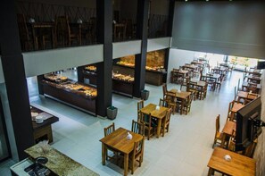 A spacious restaurant with multiple dining areas, a central buffet, and a high ceiling. - Hotel Trilhos de Minas (São João del Rei)