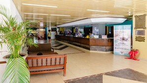 A reception area with a wooden bench, a large potted plant, and a reception desk. - Hotel Luz y Fuerza Villa Giardino (Villa Giardino)