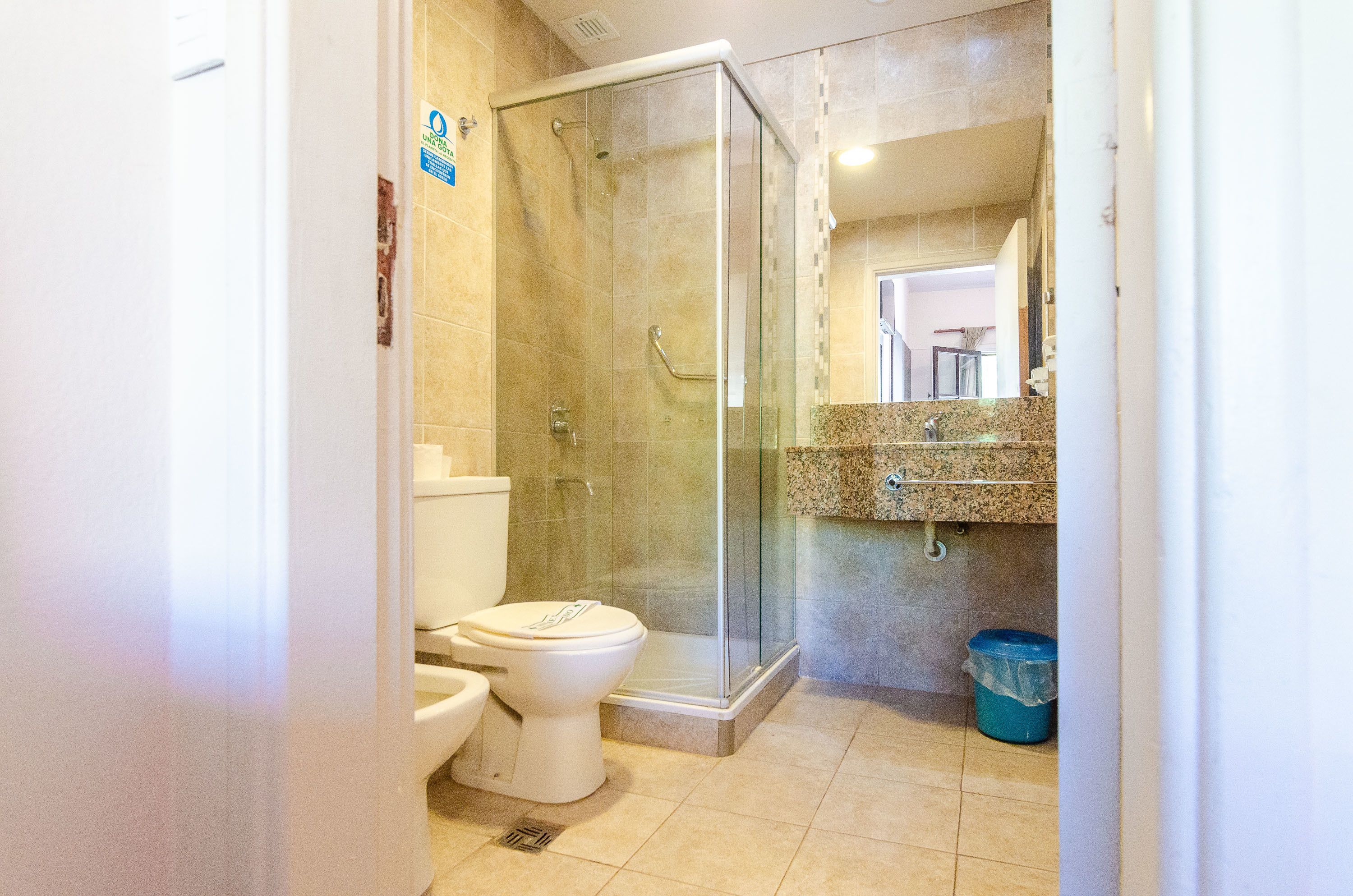 Une salle de bain moderne avec une douche à parois de verre, des toilettes et un lavabo doté d’un plan de travail en granit.