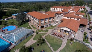 A large building with multiple red-tiled roofs, a swimming pool, and a covered outdoor area. - Hotel Luz y Fuerza Villa Giardino (Villa Giardino)